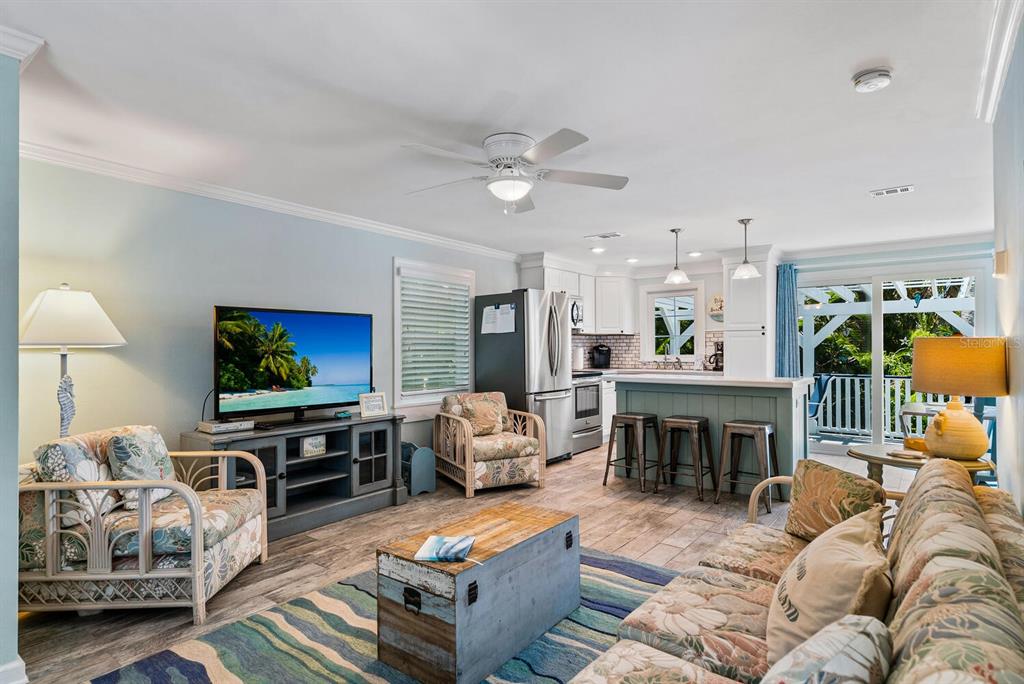A living room with floral furniture, a wooden trunk coffee table, and an open kitchen — 305 57TH STREET UNIT B, HOLMES BEACH, FL