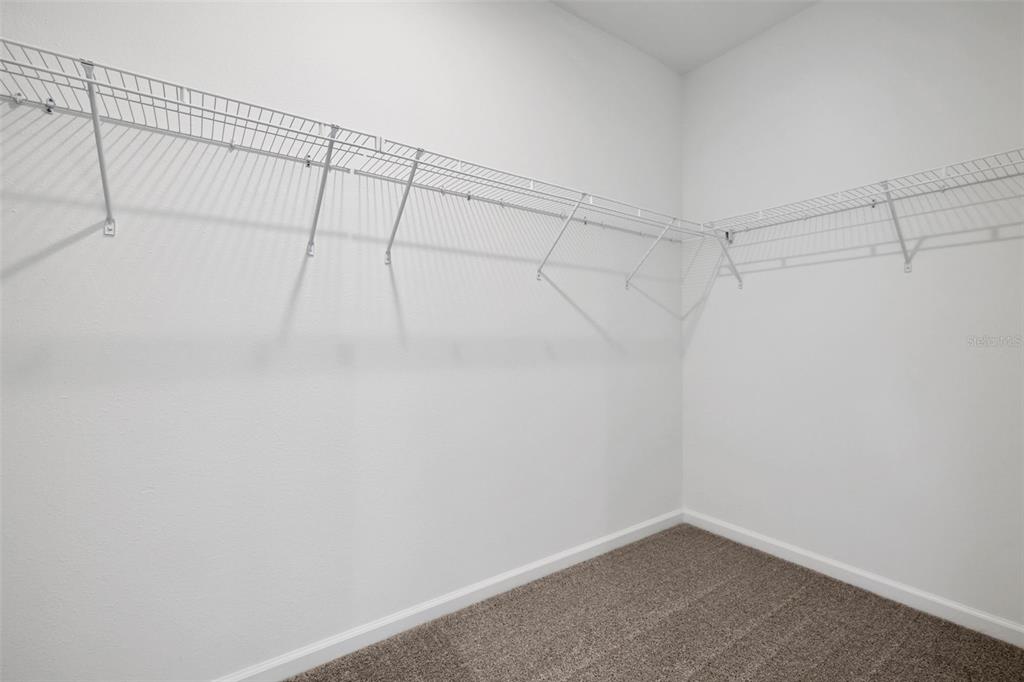 A walk-in closet with white walls, carpeted flooring, and white wire shelving — 775 FARMFIELD DRIVE, ST AUGUSTINE, FL