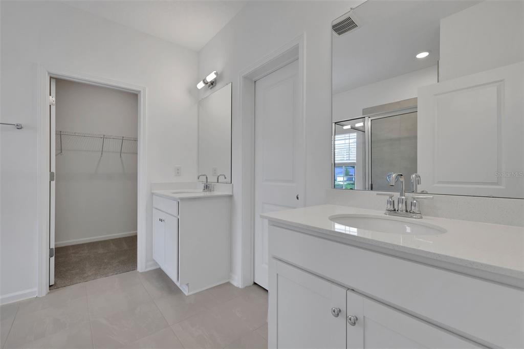 A bathroom features dual white vanities with quartz countertops, a walk-in closet, and tile flooring — 775 FARMFIELD DRIVE, ST AUGUSTINE, FL