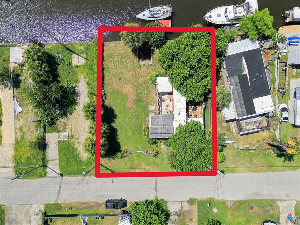 An aerial view shows a rectangular waterfront lot with a house, trees, and a yard — 6732 FLICKER LANE, HUDSON, FL