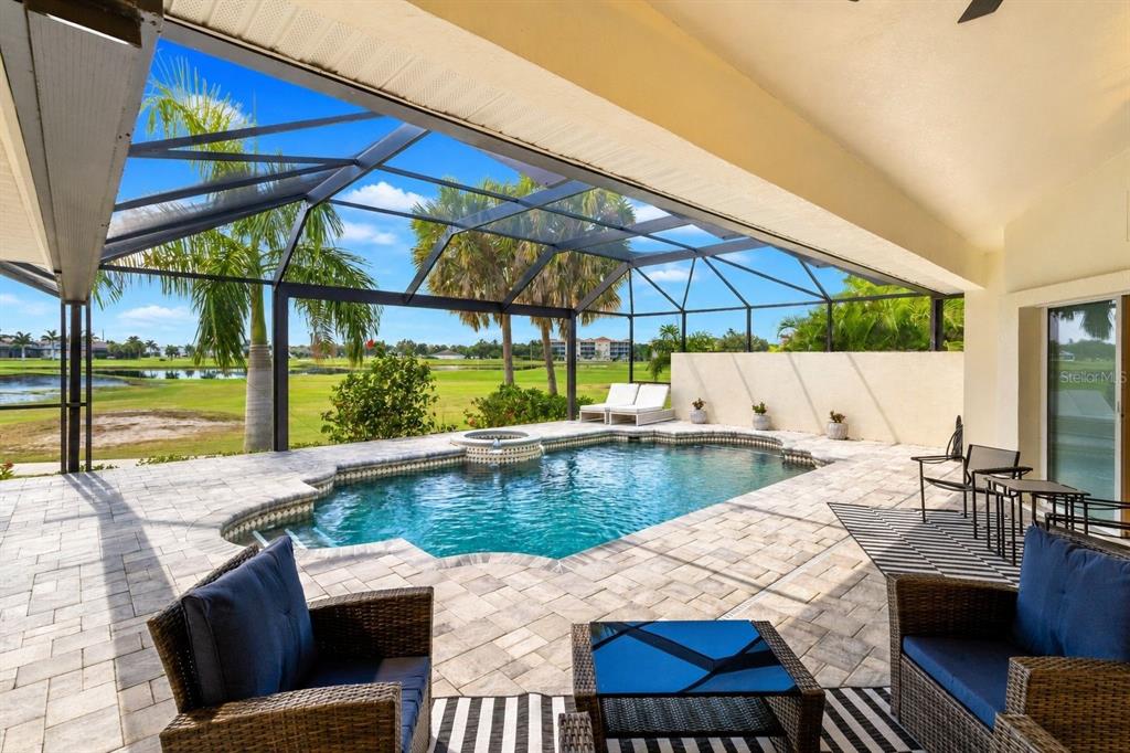 A covered patio with a swimming pool, spa, and views of a golf course — 495 CORAL CREEK DRIVE, PLACIDA, FL