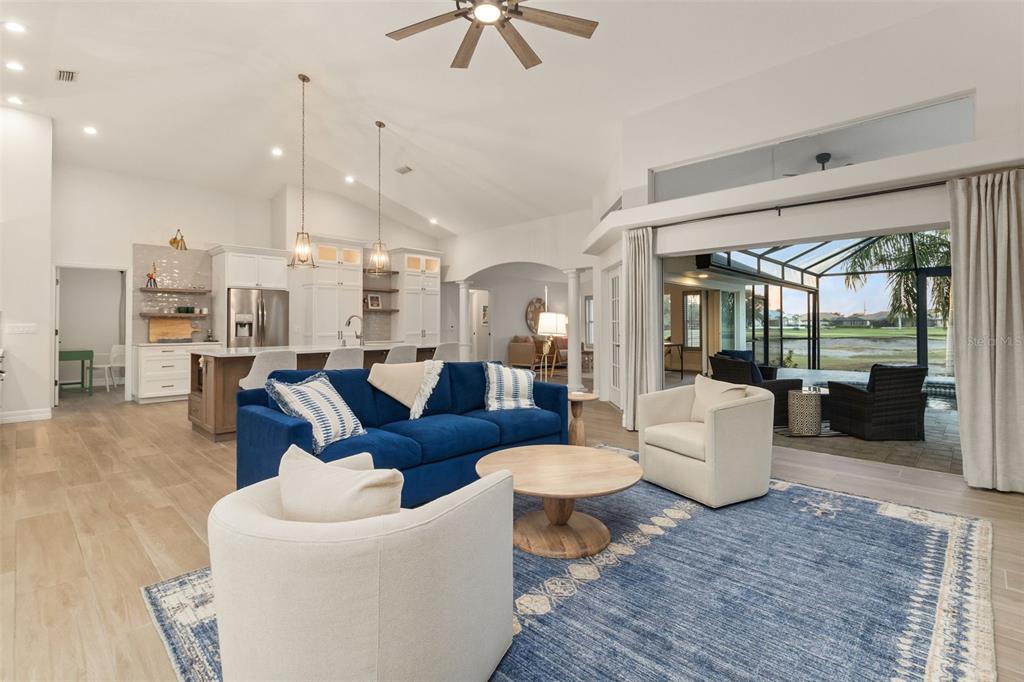 A bright open-concept living room and kitchen featuring a blue sofa and pool view — 495 CORAL CREEK DRIVE, PLACIDA, FL