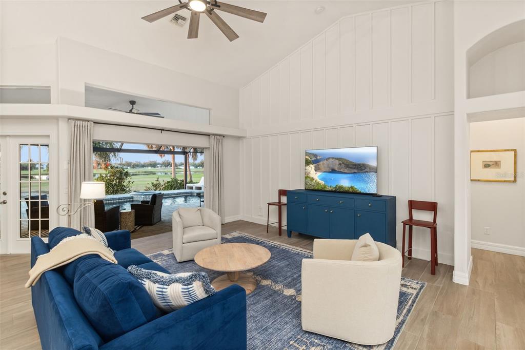 A living room with a blue sofa, two armchairs, a television, and a pool view — 495 CORAL CREEK DRIVE, PLACIDA, FL