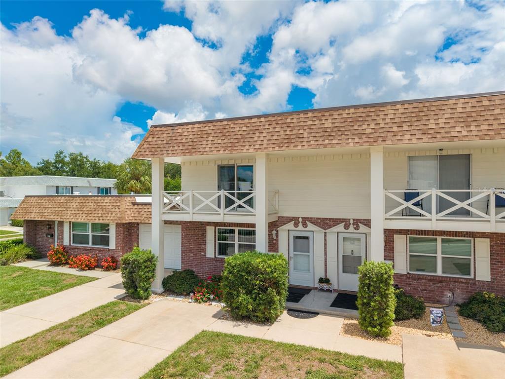 A two-story residential building with brick siding, white balconies, and a brown shingled roof — 802 MINDY COURT UNIT 802, LARGO, FL