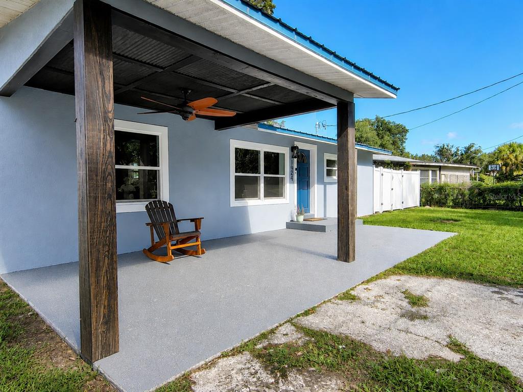 A blue house features a covered front porch with a wooden rocking chair and ceiling fan — 1924 CR 439C, LAKE PANASOFFKEE, FL