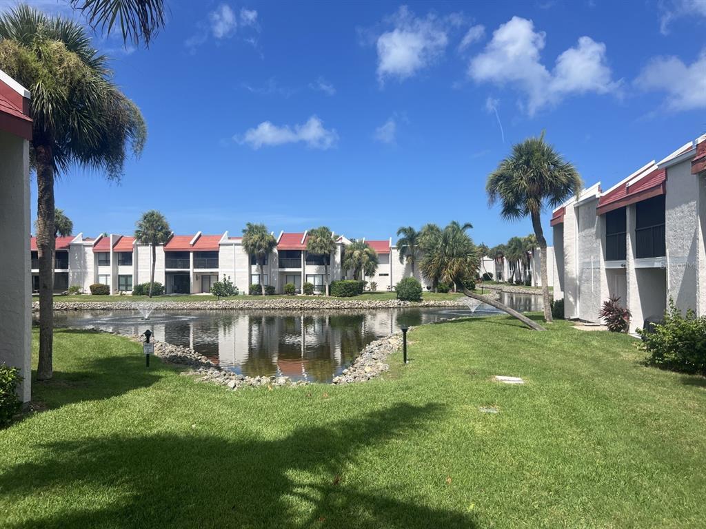 A view of a pond surrounded by apartment buildings and palm trees on a sunny day — 1801 GULF DRIVE N UNIT 184, BRADENTON BEACH, FL