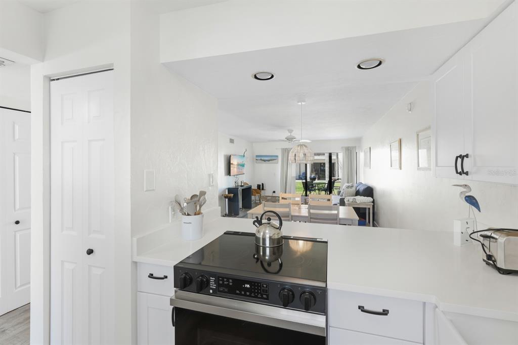 A white kitchen features a farmhouse sink, stainless steel appliances, and dark hardware — 1801 GULF DRIVE N UNIT 184, BRADENTON BEACH, FL