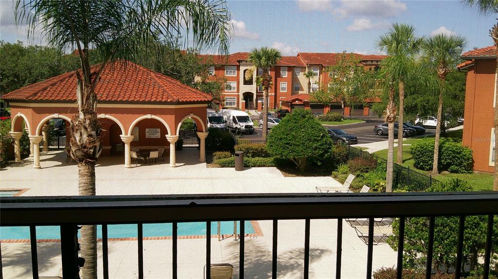 A view from a balcony overlooking a swimming pool, a pavilion, and apartment buildings — 5518 METROWEST BOULEVARD UNIT 207, ORLANDO, FL