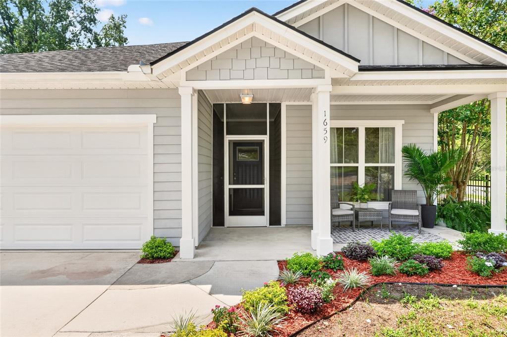 The exterior of a single-story house features gray siding, a covered porch, and a garage — 1659 NW 34TH AVENUE, GAINESVILLE, FL