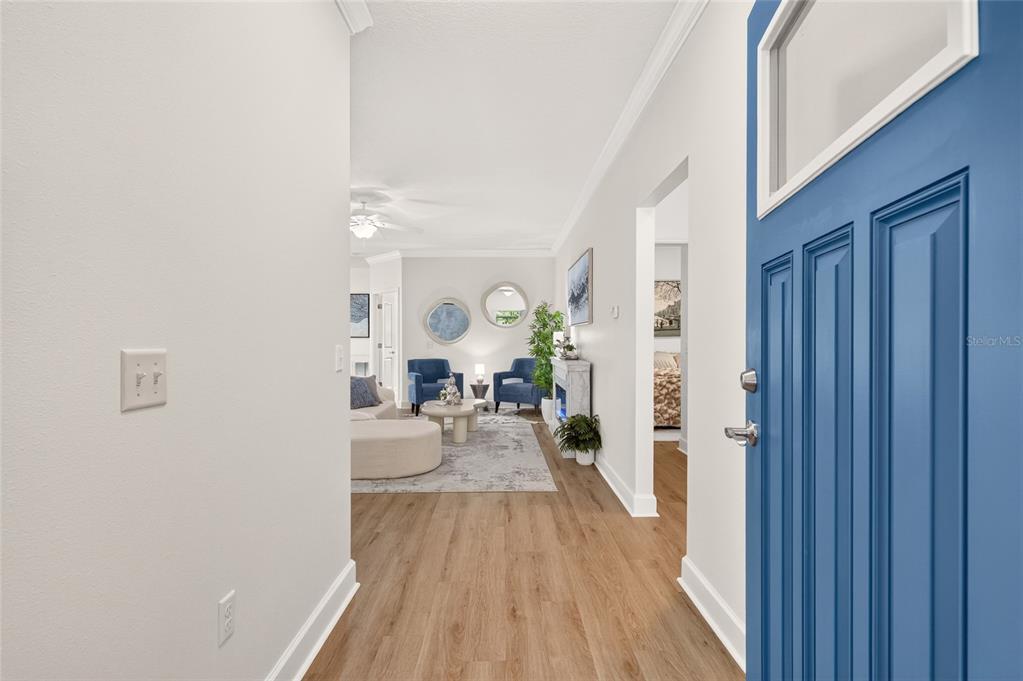 A view from an open blue front door into a living room with wood flooring — 1659 NW 34TH AVENUE, GAINESVILLE, FL