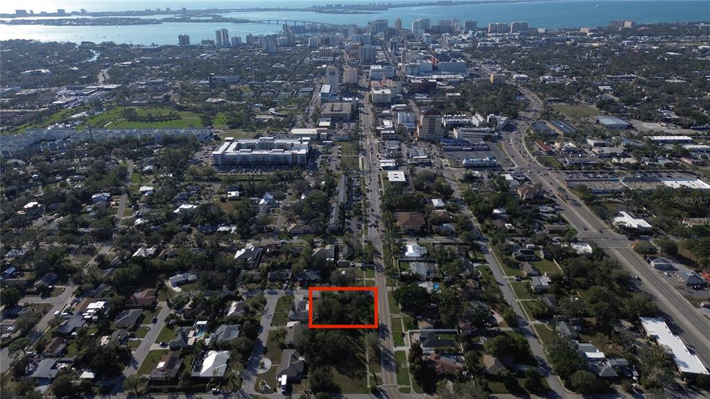 An aerial view shows a vacant, tree-covered lot outlined in red within a residential neighborhood — 2450 RINGLING BOULEVARD, SARASOTA, FL