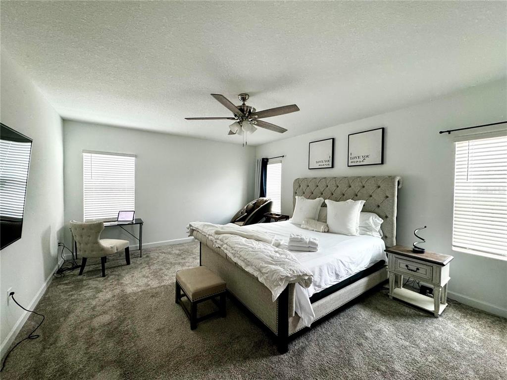 A bedroom features a tufted headboard, a ceiling fan, a desk, and carpeted flooring — 4028 REDBRIDGE LOOP, DAVENPORT, FL