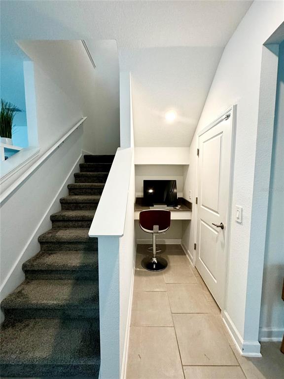 A carpeted staircase sits beside a small built-in desk nook with tile flooring — 4028 REDBRIDGE LOOP, DAVENPORT, FL