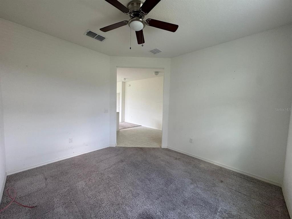A carpeted room with a ceiling fan leads into an adjacent tiled living area — 709 SARNER PASS WAY, WINTER HAVEN, FL