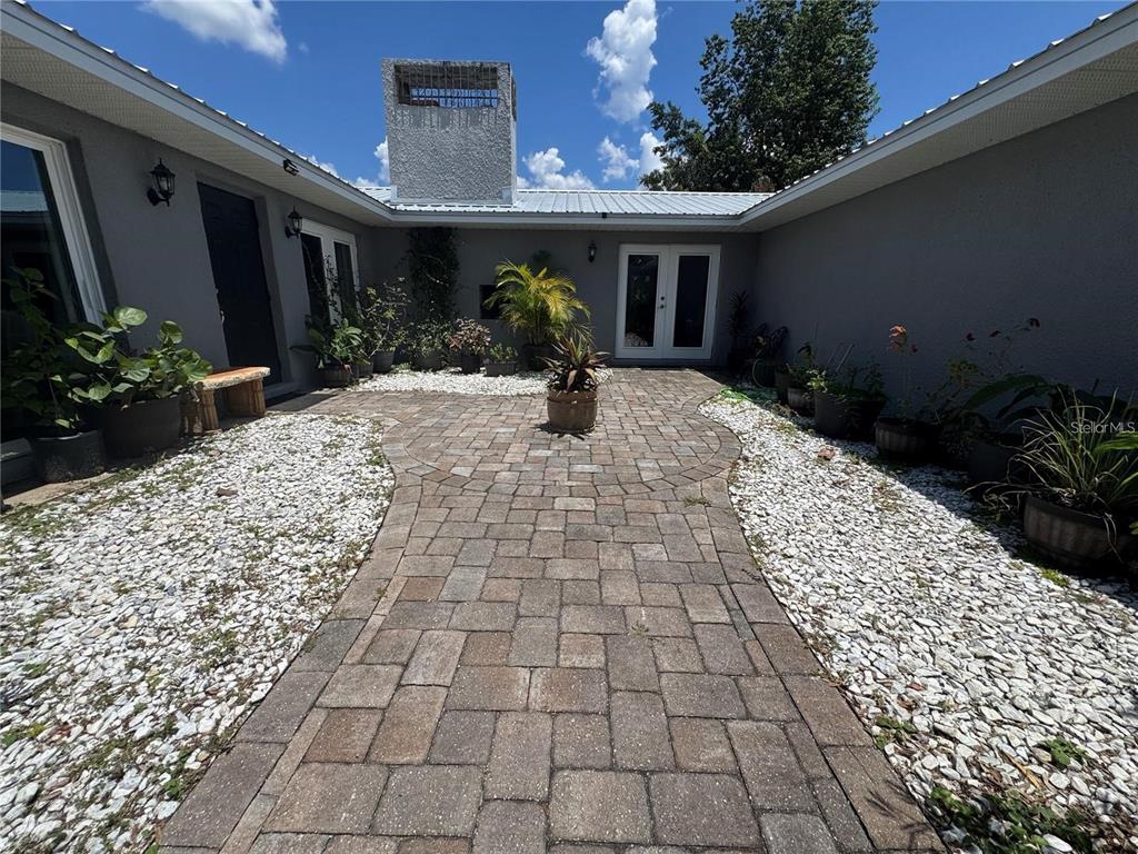 A paved courtyard features white gravel borders, potted plants, and a central chimney structure — 4925 N US HIGHWAY 441, OCALA, FL