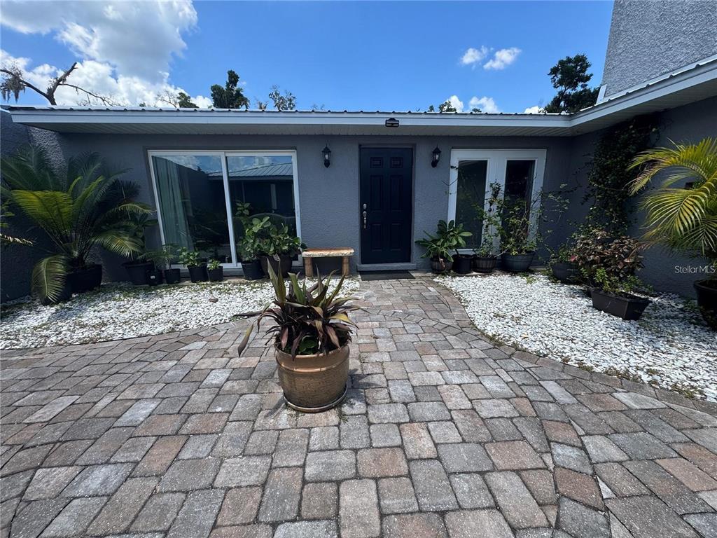 A paved walkway leads to the dark front door of a gray house with landscaping — 4925 N US HIGHWAY 441, OCALA, FL