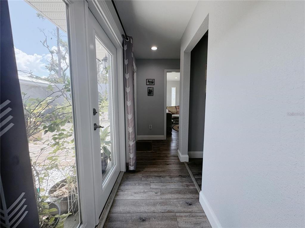 A hallway with wood-look flooring leads to a doorway, with a glass door on the left — 4925 N US HIGHWAY 441, OCALA, FL