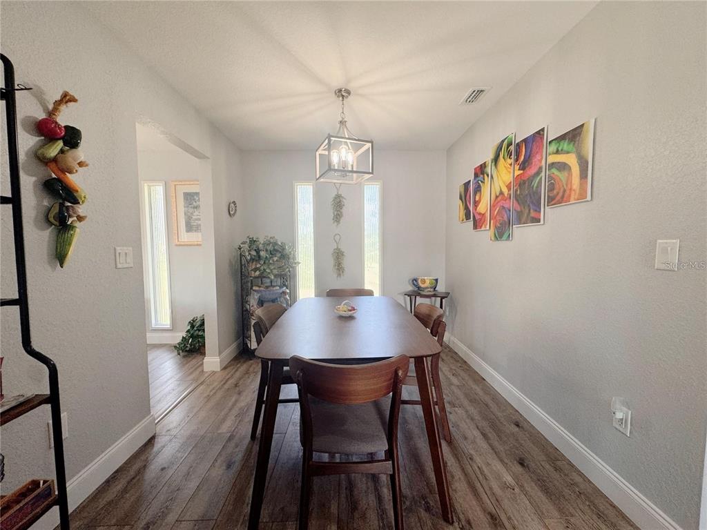 A dining room features a wooden table, chairs, a pendant light, and wall art — 4925 N US HIGHWAY 441, OCALA, FL
