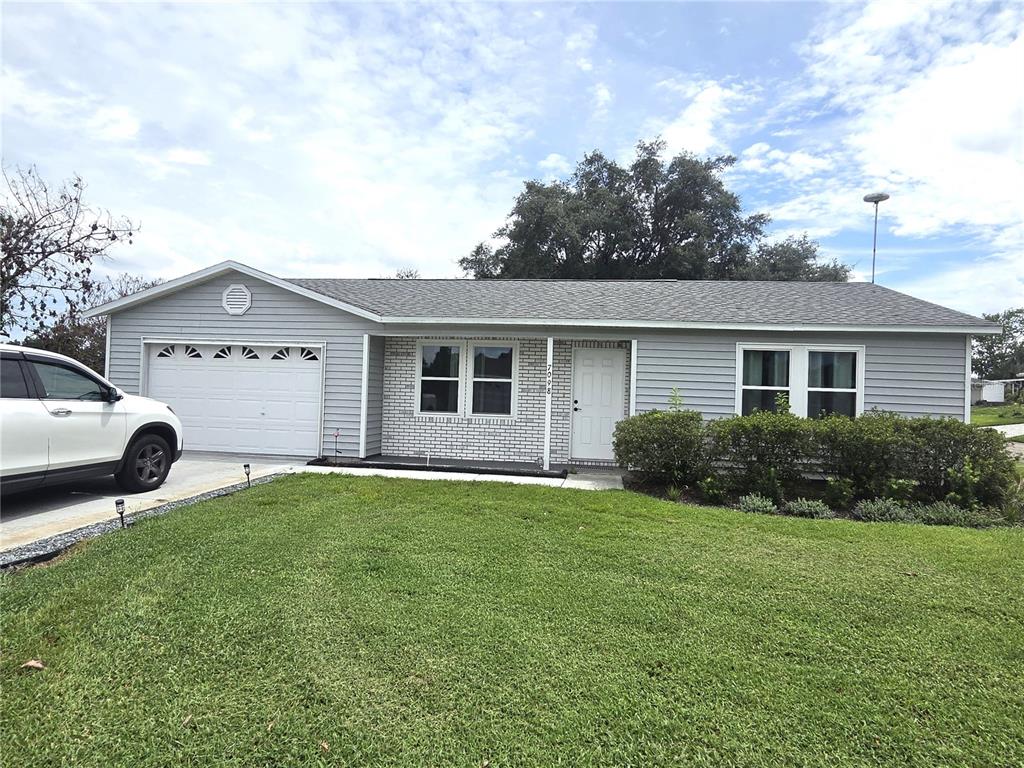 A single-story house with gray siding, a white brick facade, and an attached garage — 7098 ALAMANDA BOULEVARD W, LAKE WALES, FL