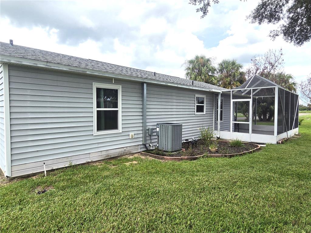 The exterior of a gray-sided house features a screened-in porch and an air conditioning unit — 7098 ALAMANDA BOULEVARD W, LAKE WALES, FL