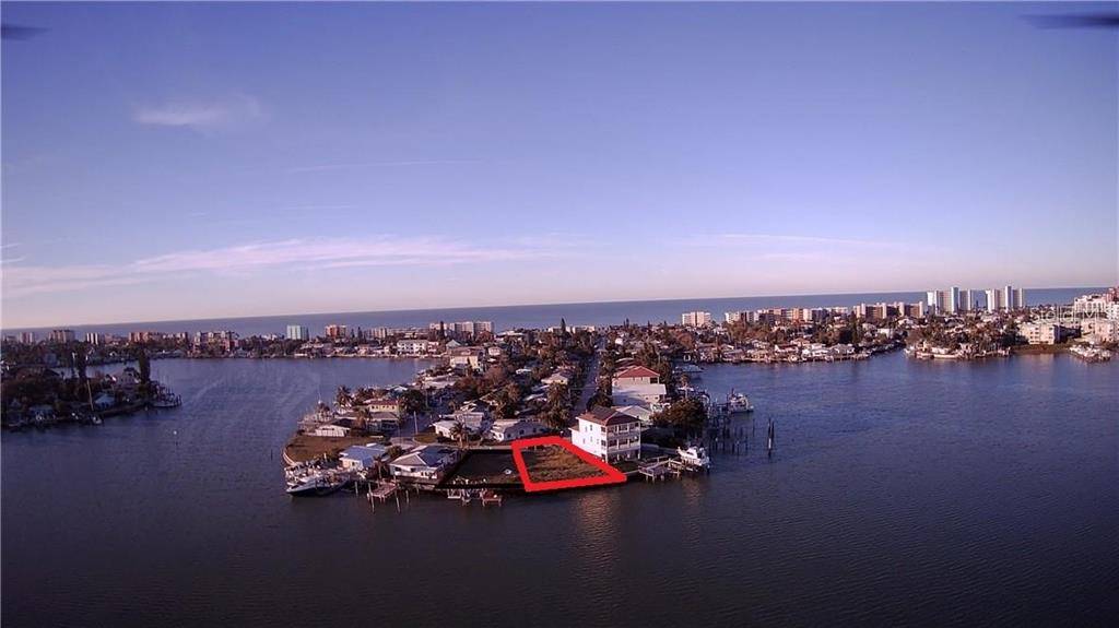 An aerial view shows a vacant waterfront lot outlined in red on a residential peninsula — 376 145TH AVENUE E, MADEIRA BEACH, FL
