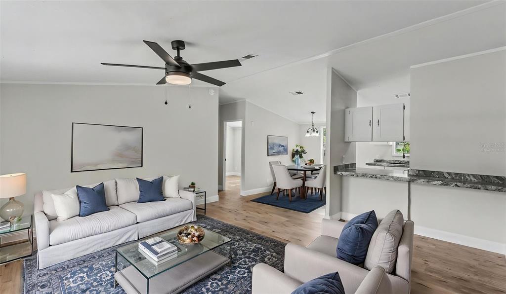 A living room with a sofa and armchairs opens to a dining area and kitchen — 1222 ROWELL STREET, AUBURNDALE, FL