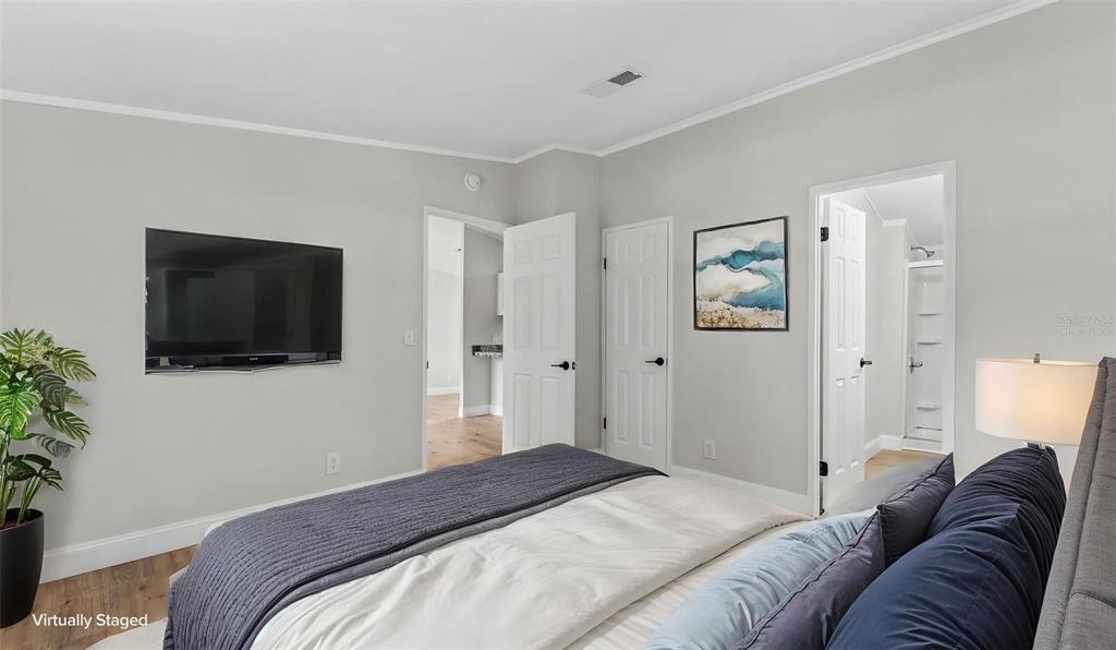 A bedroom with light gray walls, a mounted television, and two open doorways — 1222 ROWELL STREET, AUBURNDALE, FL