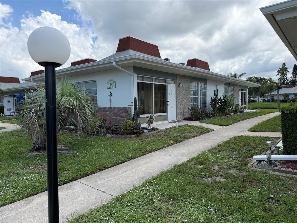 A single-story residential building with a white exterior, stone accents, and a red roof — 4340 TAHITIAN GARDENS CIRCLE UNIT D, HOLIDAY, FL