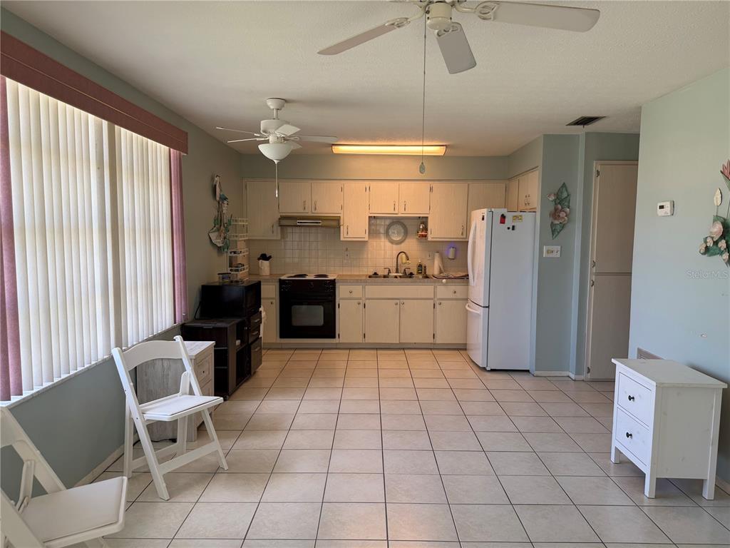 A kitchen with white cabinets, tile flooring, and a white refrigerator in an open-concept space — 4340 TAHITIAN GARDENS CIRCLE UNIT D, HOLIDAY, FL