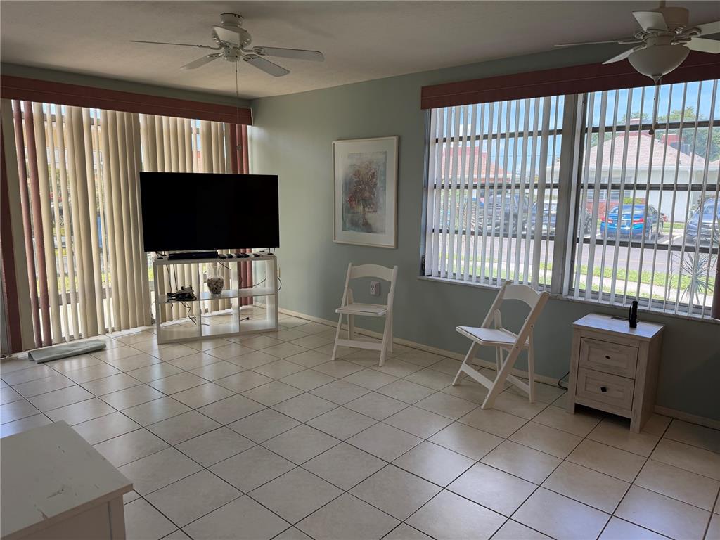 A living room with tile flooring, two ceiling fans, vertical blinds, and a television stand — 4340 TAHITIAN GARDENS CIRCLE UNIT D, HOLIDAY, FL