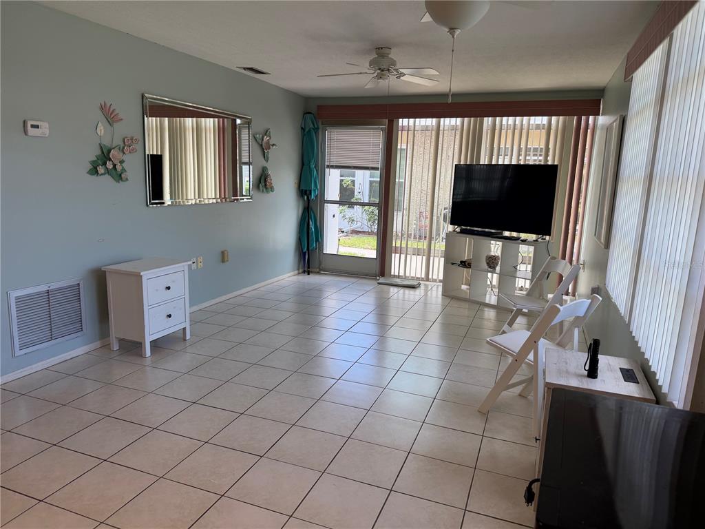 A sunroom with light blue walls, tiled floors, a ceiling fan, and a television stand — 4340 TAHITIAN GARDENS CIRCLE UNIT D, HOLIDAY, FL