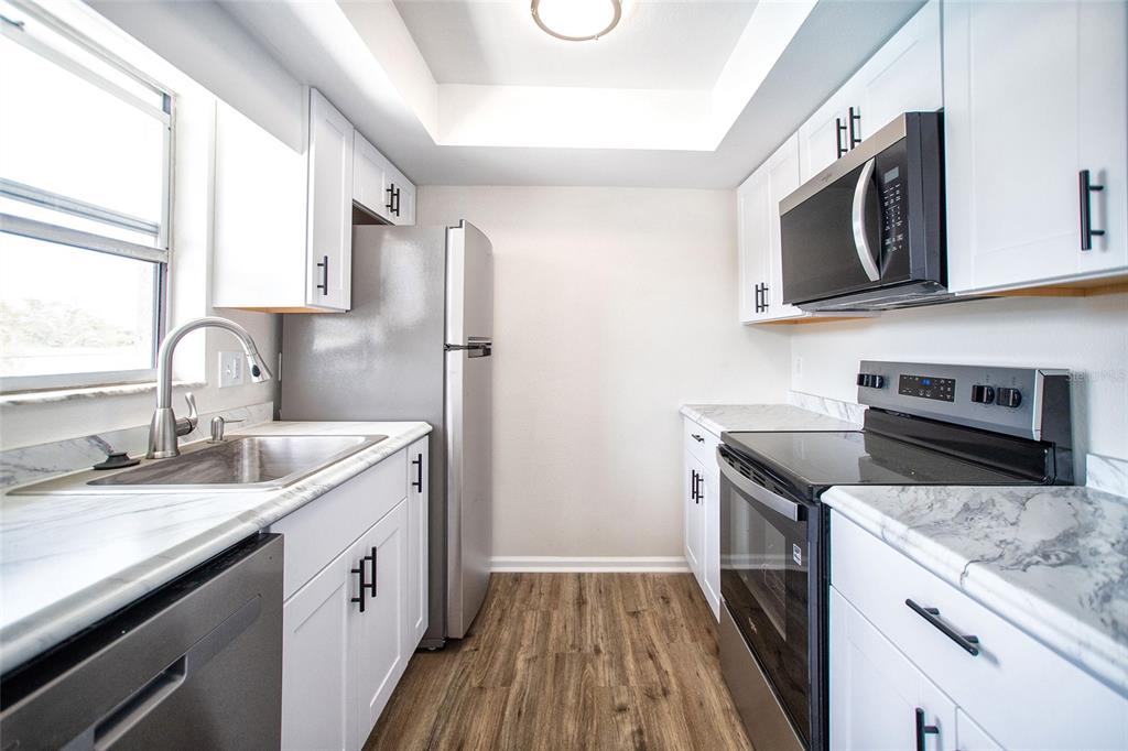 An empty room with light-colored walls, wood-look flooring, a ceiling fan, and a front door — 6062 22ND AVENUE N UNIT 5, ST PETERSBURG, FL
