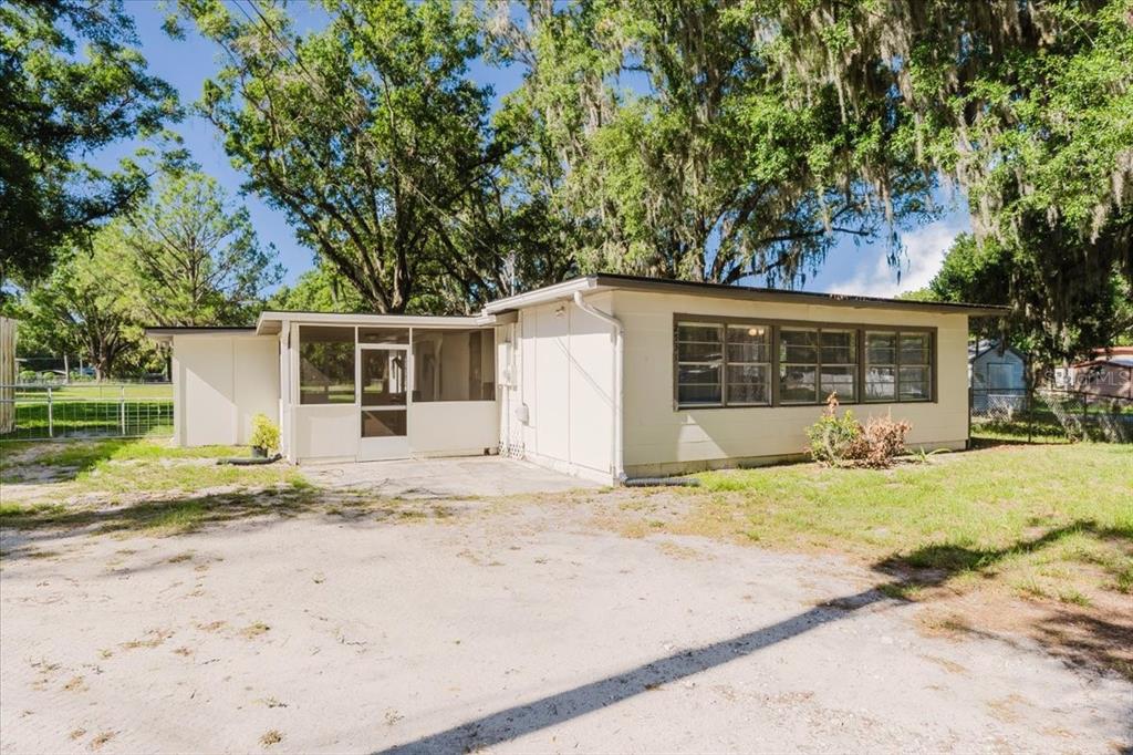 A single-story house with a screened-in porch and large windows sits on a dirt lot — 2531 HEBB ROAD, AUBURNDALE, FL
