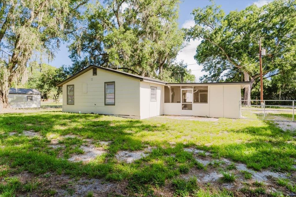 A one-story house with light-colored siding, a screened porch, and a large grassy yard — 2531 HEBB ROAD, AUBURNDALE, FL