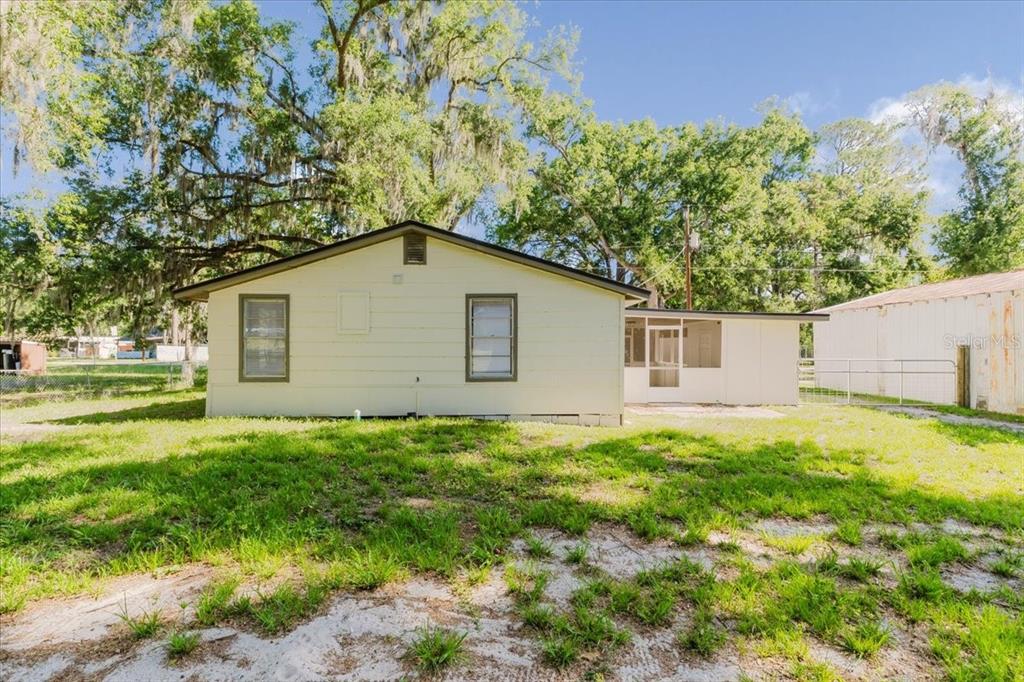 The exterior of a single-story house with light siding, two windows, and a screened porch — 2531 HEBB ROAD, AUBURNDALE, FL