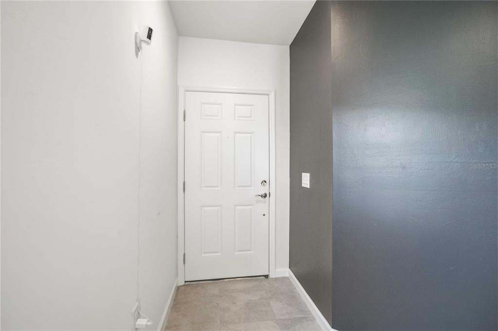 A white door stands at the end of a small entryway with gray tile flooring — 6548 SILVERSTAR DRIVE, SARASOTA, FL