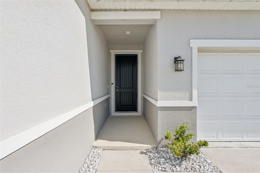 The exterior view shows a black front door, a garage, and a small landscaped area — 1682 LITTLELEAF BOXWOOD LOOP, MASCOTTE, FL
