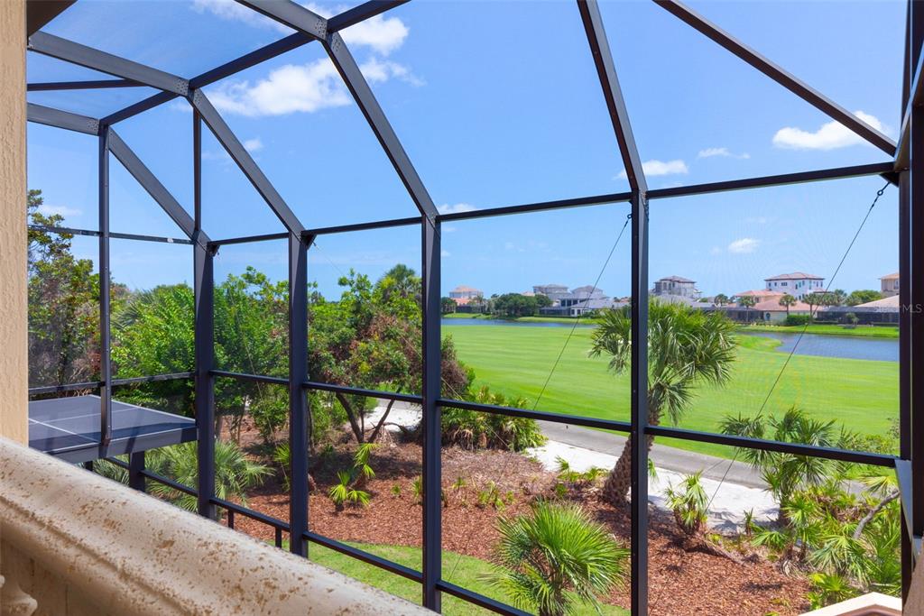 A view from a screened-in balcony overlooking a golf course, pond, and residential homes — 44 OCEAN OAKS LANE, PALM COAST, FL