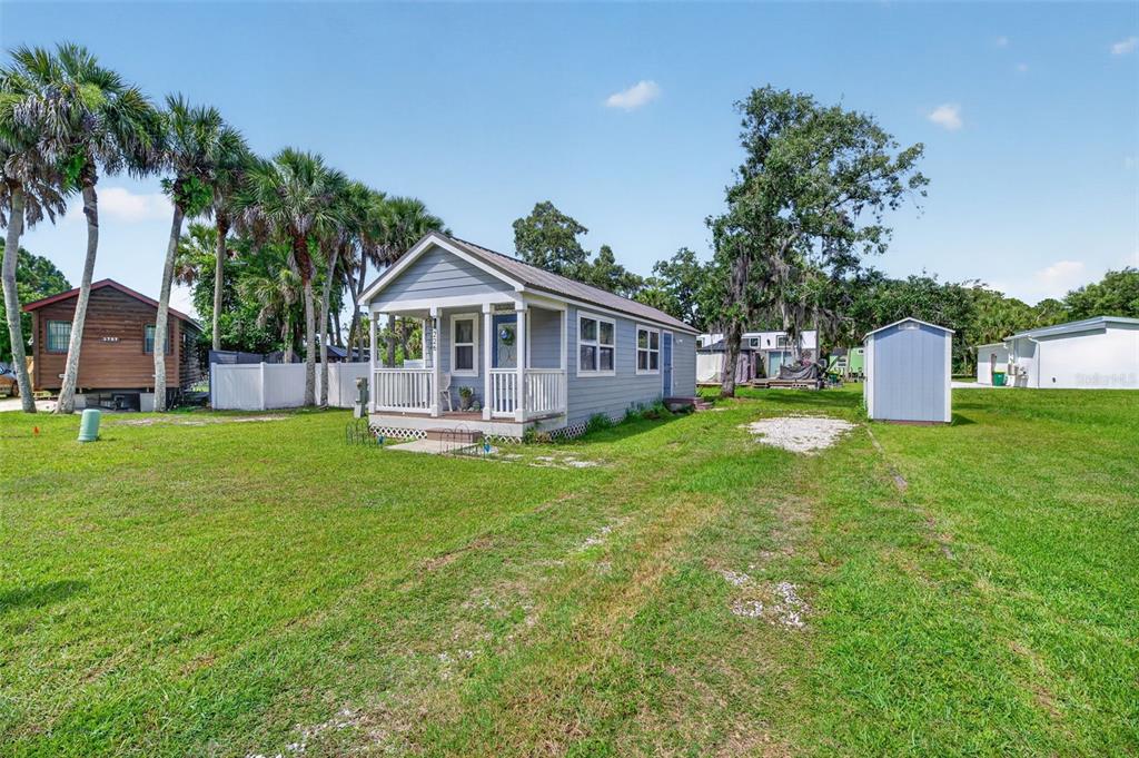 A light blue cottage with a front porch sits on a grassy lot with palm trees — 226 FLAMINGO DRIVE, COCOA, FL