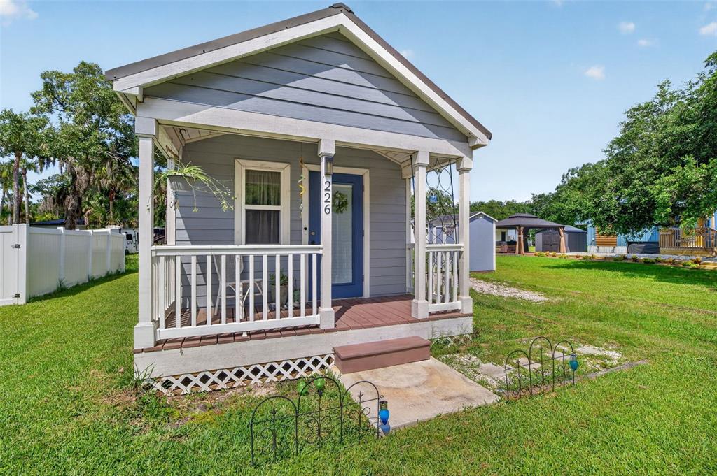 A small, gray, single-story house with a front porch and white railings sits on grass — 226 FLAMINGO DRIVE, COCOA, FL
