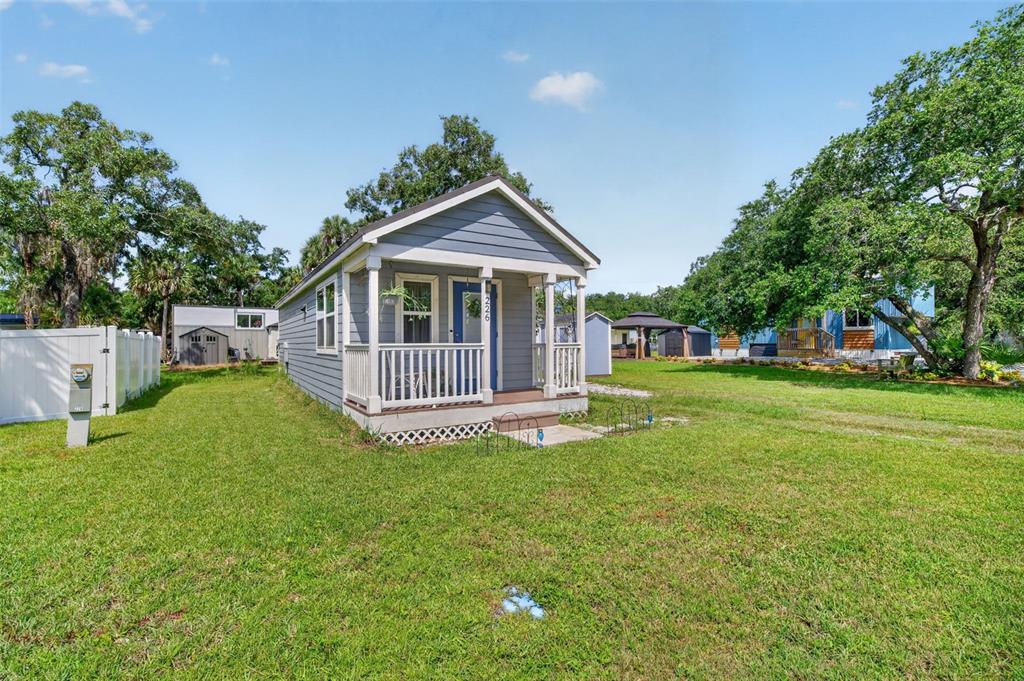 A small, blue, single-story house with a front porch sits on a grassy lot — 226 FLAMINGO DRIVE, COCOA, FL