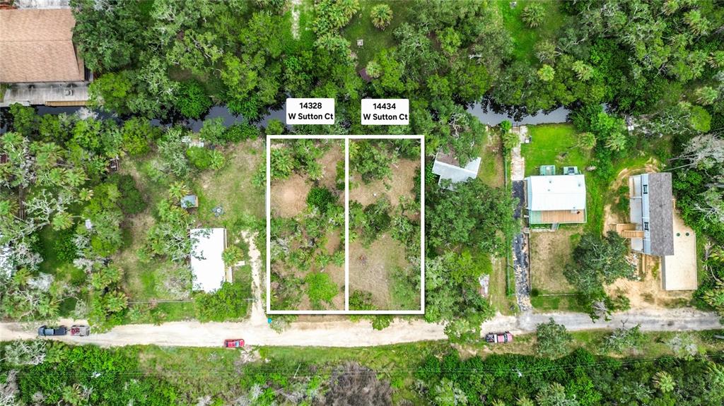 This aerial view shows two adjacent vacant lots outlined in white along a dirt road — 14328 W SUTTON COURT, CRYSTAL RIVER, FL