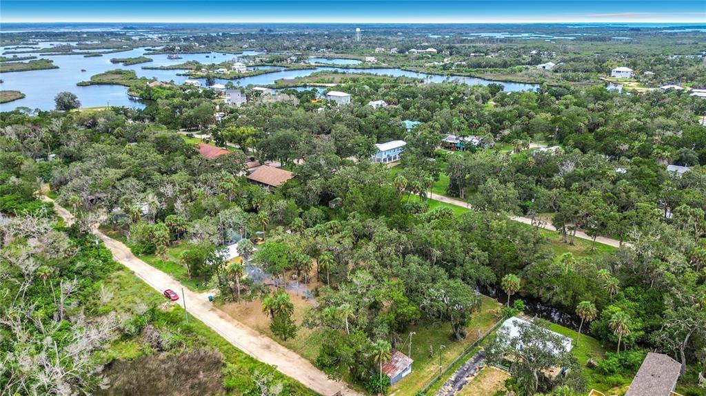 An aerial view shows a rural neighborhood with houses nestled among dense trees and waterways — 14328 W SUTTON COURT, CRYSTAL RIVER, FL