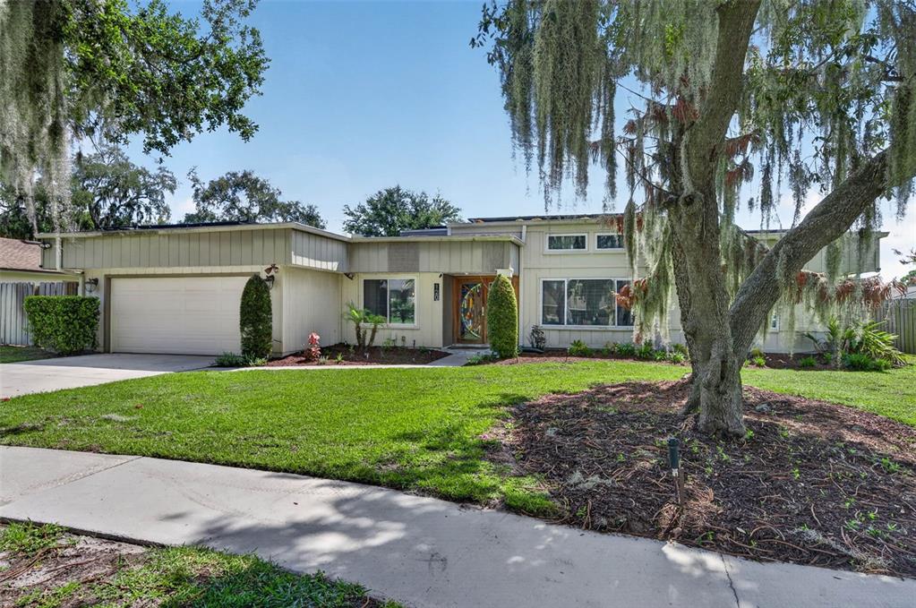 A single-story house with a two-car garage, light-colored siding, and a large tree in front — 120 SLADE DRIVE, LONGWOOD, FL