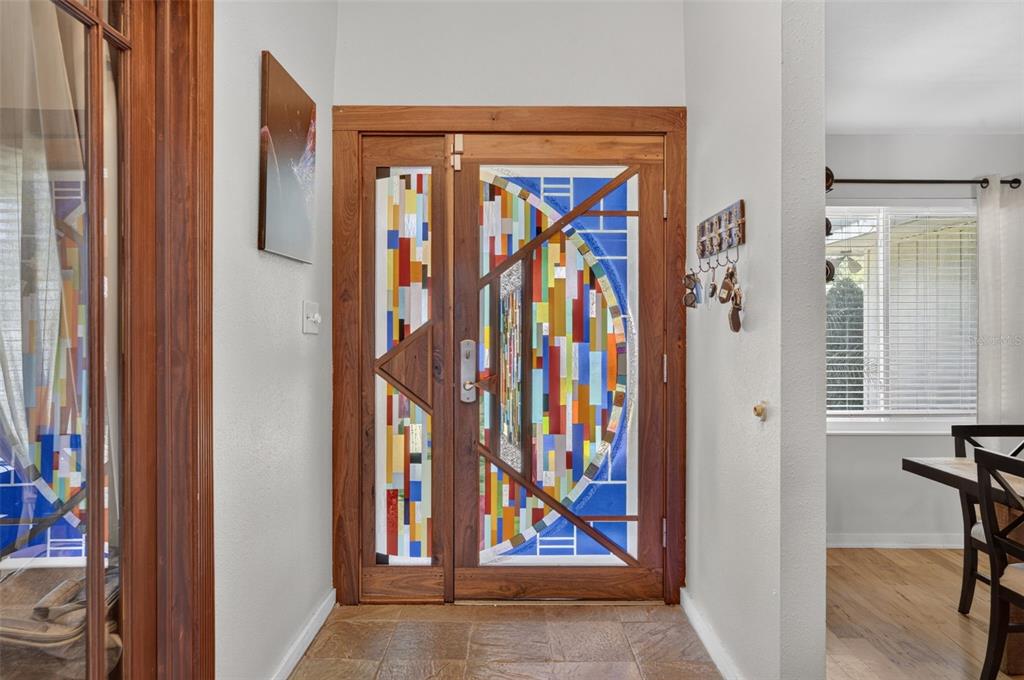 An entryway features a wooden door with colorful stained glass panels and tiled flooring — 120 SLADE DRIVE, LONGWOOD, FL