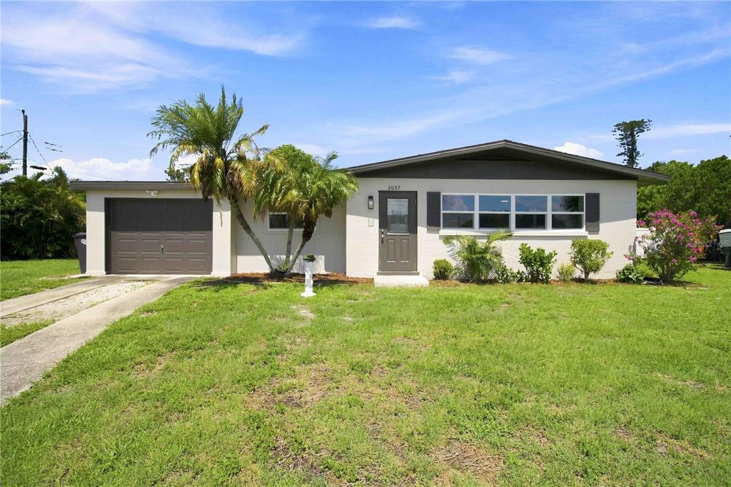 A single-story house with a light-colored exterior, a garage, and a front lawn — 2057 GARDEN PARKWAY, BRADENTON, FL