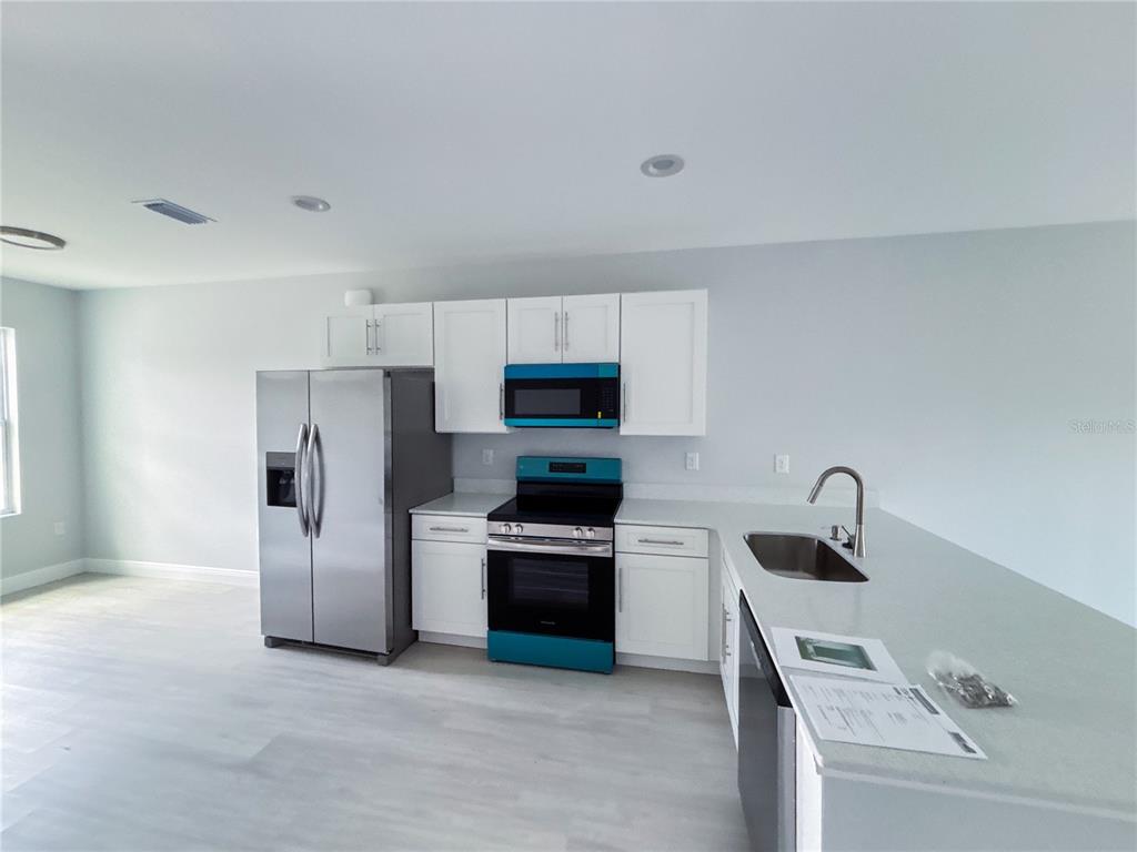 A kitchen features white cabinets, stainless steel appliances, and a light-colored countertop — 14 TROUT WAY, KISSIMMEE, FL