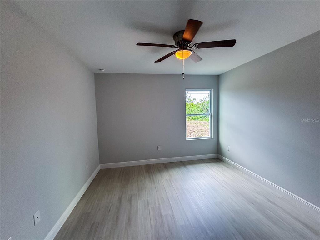 An empty bedroom features light gray walls, wood-look flooring, and a ceiling fan — 14 TROUT WAY, KISSIMMEE, FL