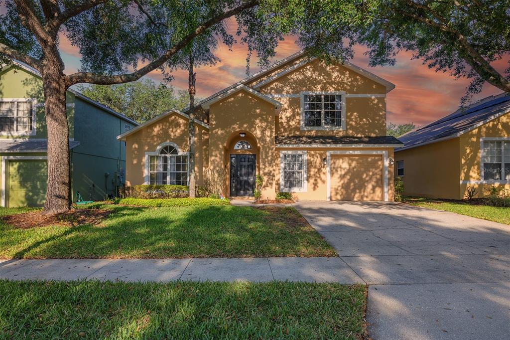 A two-story yellow stucco house with a front lawn, driveway, and a single-car garage — 17833 WOODCREST WAY, CLERMONT, FL