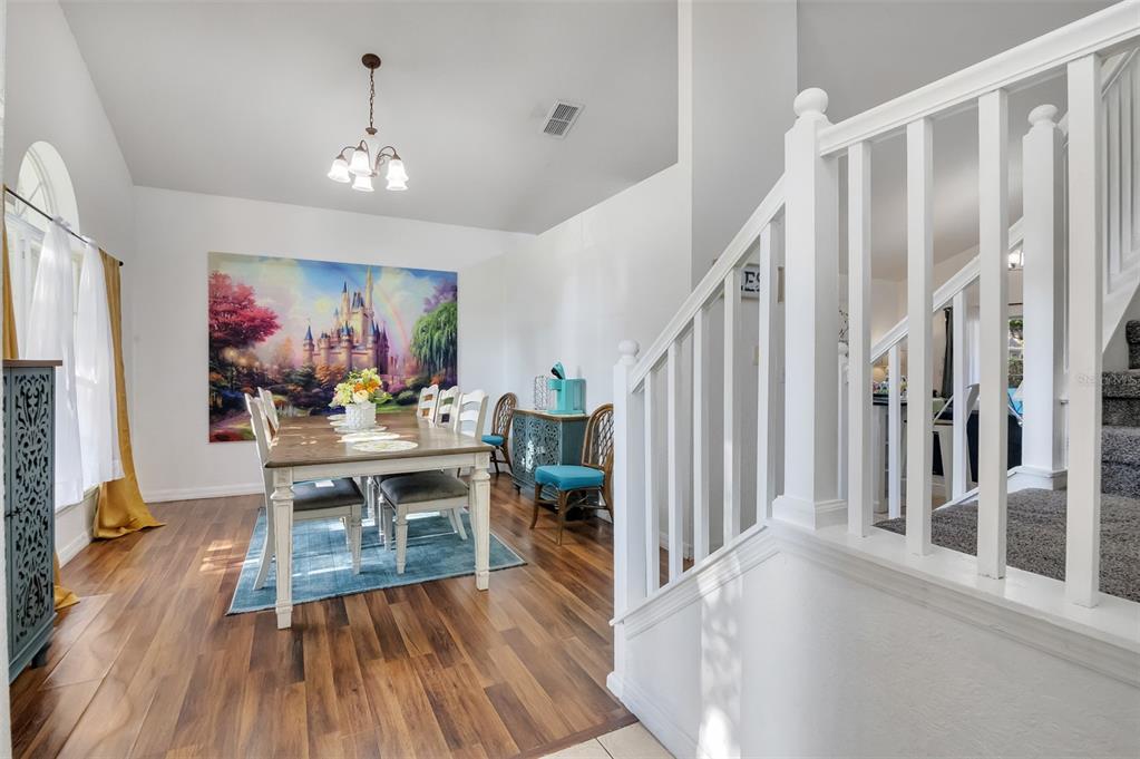 A dining room features a large castle wall mural, wood flooring, and a white staircase — 17833 WOODCREST WAY, CLERMONT, FL